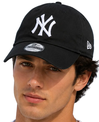 models wearing black New York Yankees baseball caps with white embroidered logos, photographed against a clear light blue sky.