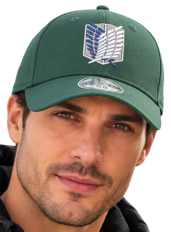 A man and a woman wearing matching green baseball caps with the Attack on Titan Scout Regiment logo, posed outdoors against a blue sky.
