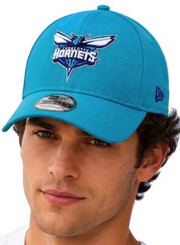  model wearing a bright turquoise blue Charlotte Hornets baseball cap against a clear blue sky background.