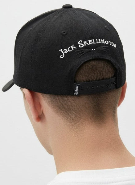 A man viewed from behind wearing a black baseball cap with 'Jack Skellington' embroidered in white script on the back, paired with a white t-shirt against a light gray background.