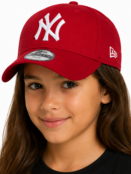 Two children, a boy and a girl, wearing matching red New York Yankees baseball caps with white embroidered logos. The New Era brand logo is visible on the side of the caps.