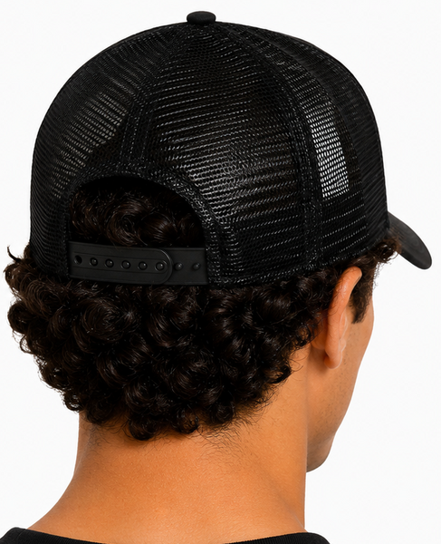 A black New Era trucker cap shown on a model from both the front-left and back angles. The front panel features a tonal black embroidered New York Yankees logo, and the back has black mesh panels and an adjustable strap.