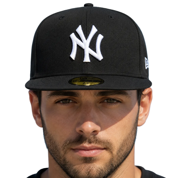 A man wearing a black New York Yankees fitted baseball cap with a white embroidered NY logo, photographed against a clear blue sky.