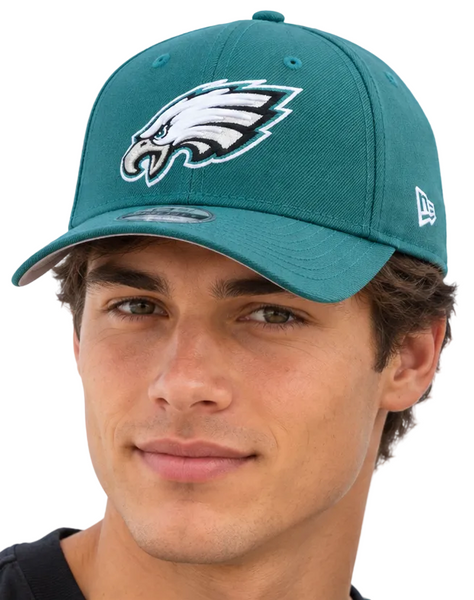 Two models wearing Philadelphia Eagles baseball caps with the New Era 9FIFTY logo, set against a light blue sky background.
