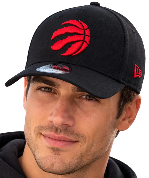 Two models wearing black Toronto Raptors baseball caps with a red embroidered logo and a red New Era flag on the side, set against a clear blue sky.